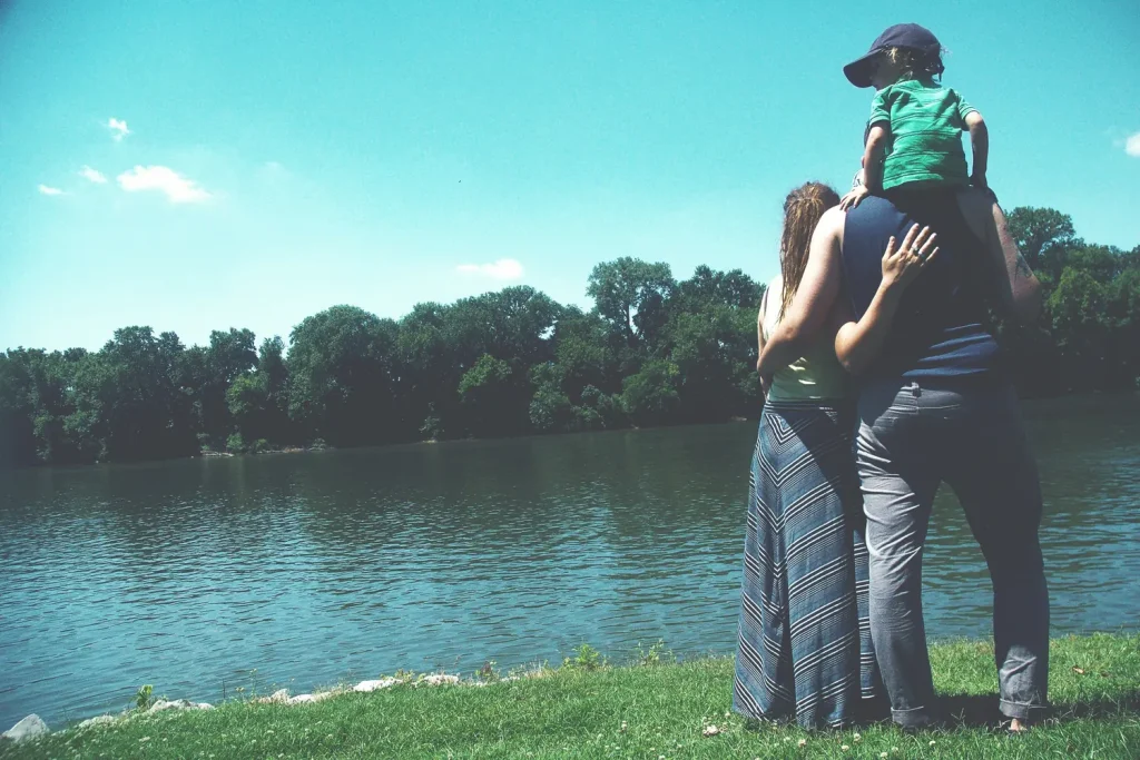 Un père porte son enfant sur les épaules au bord d’un lac