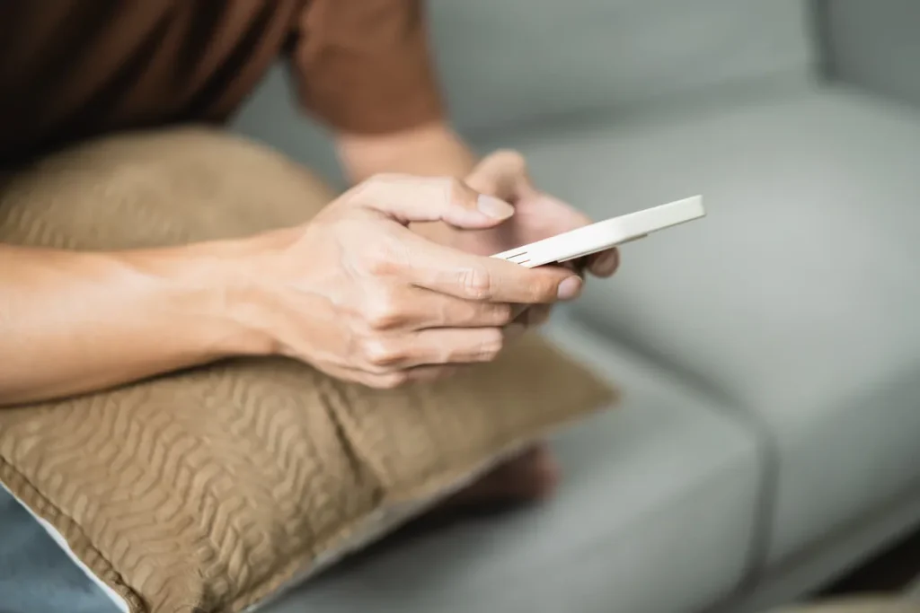 Personne utilisant son smartphone allongée sur un canapé
