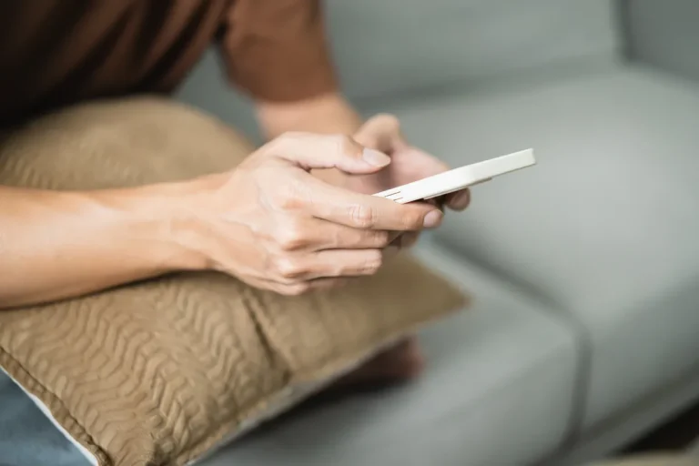Personne utilisant son smartphone allongée sur un canapé