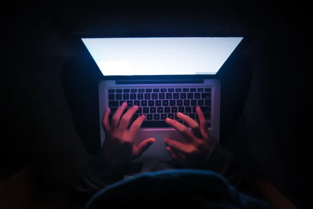 Personne regardant des vidéos sur un ordinateur portable dans le noir