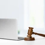 Marteau de juge posé à côté d'un ordinateur portable, litige autour d'un nom de domaine