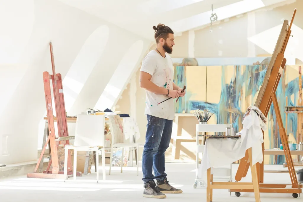 Artiste peintre tenant ses pinceaux dans son atelier, auteur d'œuvres protégées par le droit d'auteur