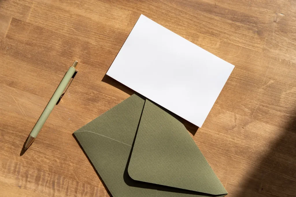 Enveloppe verte et carte vierge sur une table en bois, envoi d'une mise en demeure de payer