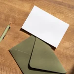 Enveloppe verte et carte vierge sur une table en bois, envoi d'une mise en demeure de payer