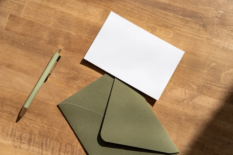 Enveloppe verte et carte vierge sur une table en bois, envoi d'une mise en demeure de payer