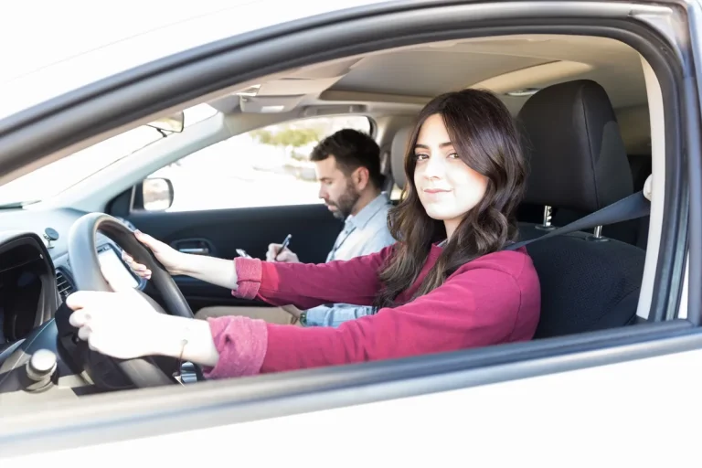 Élève conductrice au volant avec son moniteur d'auto-école qui prend des notes