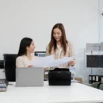 Deux femmes travaillant ensemble sur des documents dans un bureau moderne