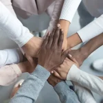 Mains de collègues réunies les unes sur les autres, symbole d'égalité contre la discrimination