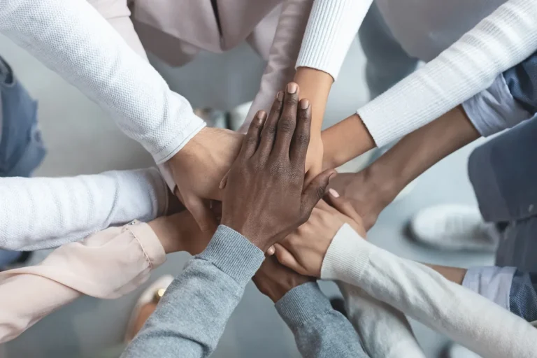 Mains de collègues réunies les unes sur les autres, symbole d'égalité contre la discrimination