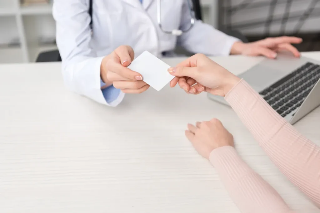 Médecin tendant une carte à un patient dans son cabinet