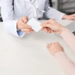Médecin tendant une carte à un patient dans son cabinet
