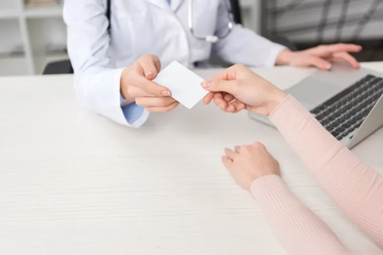 Médecin tendant une carte à un patient dans son cabinet