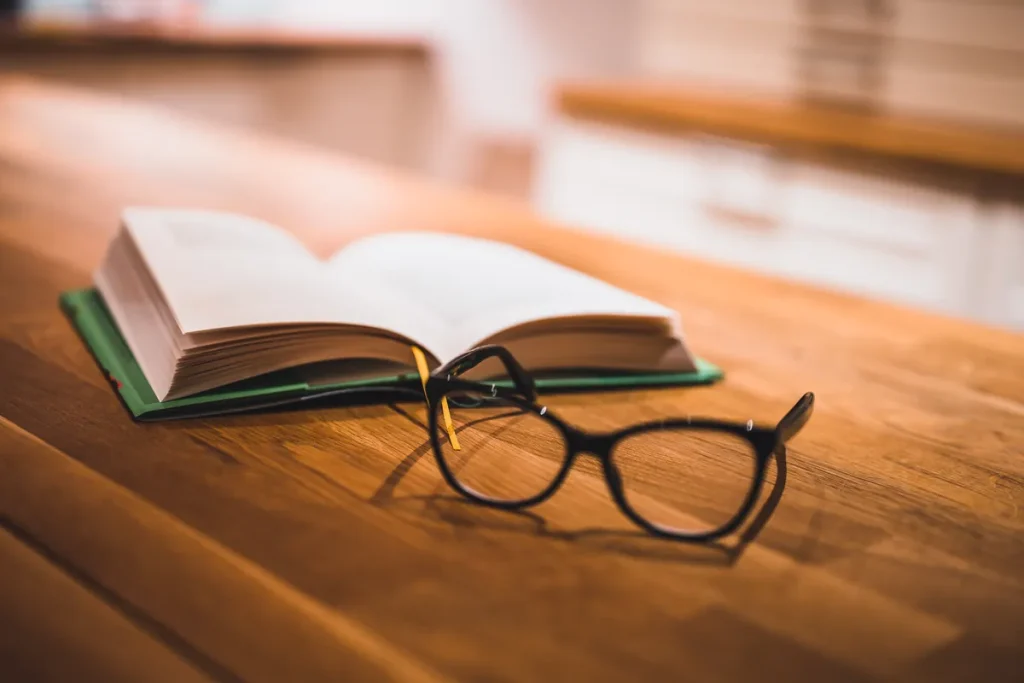 Livre ouvert et lunettes posés sur une table, consultation du Code du travail