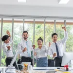 Équipe joyeuse célébrant une réussite au bureau, bien-être et psychologie positive au travail
