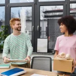 Deux collègues rangeant des dossiers et un carton au bureau, fin de période d'essai