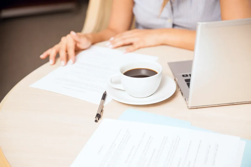 Femme préparant son CV sur ordinateur portable avec un café