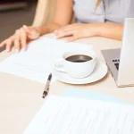 Femme préparant son CV sur ordinateur portable avec un café