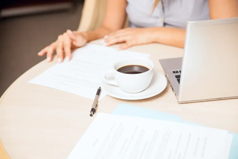 Femme préparant son CV sur ordinateur portable avec un café