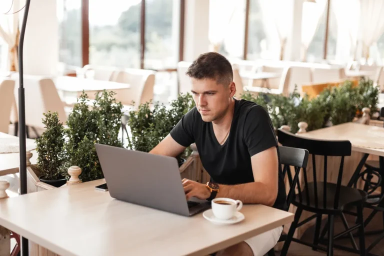 Jeune vacataire travaillant sur son ordinateur portable dans un café lumineux