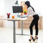 Femme travaillant debout à un bureau réglable en hauteur, bonne posture au travail