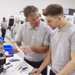 Deux techniciens étudiant des plans dans un atelier, montée en qualification professionnelle