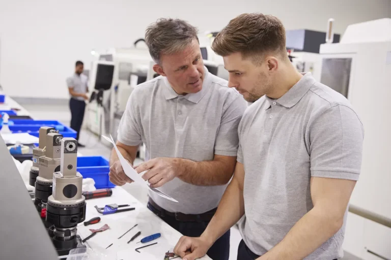 Deux techniciens étudiant des plans dans un atelier, montée en qualification professionnelle
