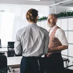 Discussion entre un salarié et son responsable dans un bureau moderne, rupture anticipée d'un CDD
