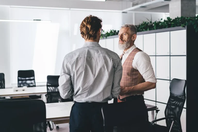 Discussion entre un salarié et son responsable dans un bureau moderne, rupture anticipée d'un CDD