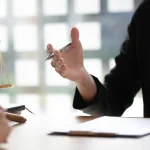 Avocat conseillant un client près d'une balance de la justice, au sujet d'un préjudice
