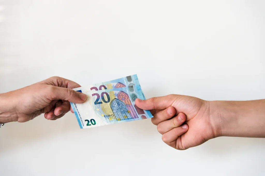 Deux mains échangeant des billets de vingt euros, comme une avance sur salaire