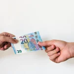 Deux mains échangeant des billets de vingt euros, comme une avance sur salaire