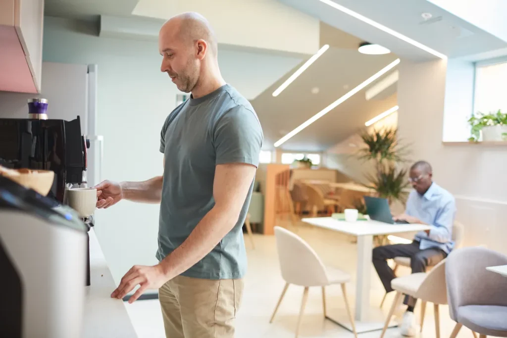 Salarié préparant un café dans l'espace pause d'une entreprise