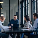 Réunion d'équipe autour d'une table dans un bureau moderne, illustrant la gestion du budget du CSE