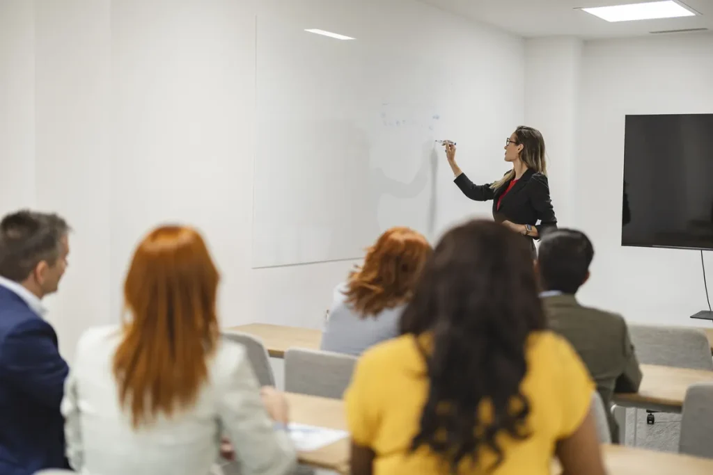 Formatrice devant un tableau blanc lors d'une session de formation professionnelle