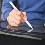 Main utilisant un stylet sur une tablette, écrit électronique