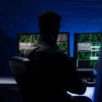 Développeur travaillant de nuit devant plusieurs écrans de code