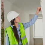 Artisan inspectant un mur abîmé lors de travaux, recherche d'un vice caché