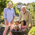 Grands-parents jouant avec leurs petits-enfants dans le jardin, transmission par l'assurance vie