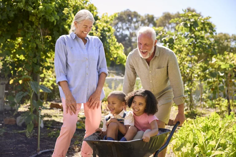 Grands-parents jouant avec leurs petits-enfants dans le jardin, transmission par l'assurance vie