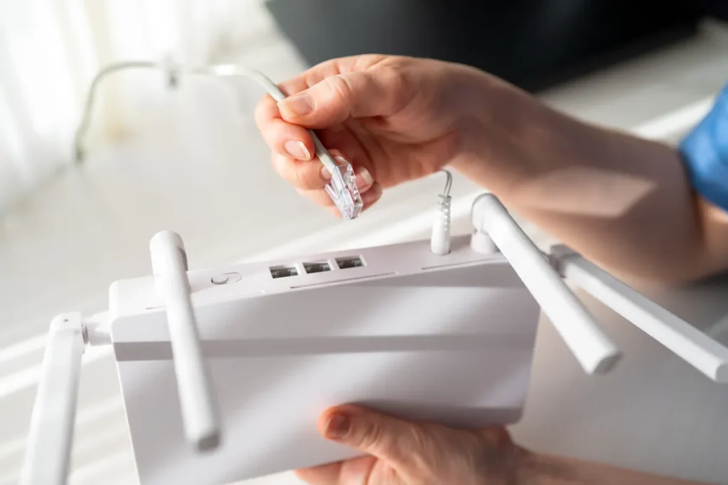 Main branchant un câble Ethernet sur une box internet blanche