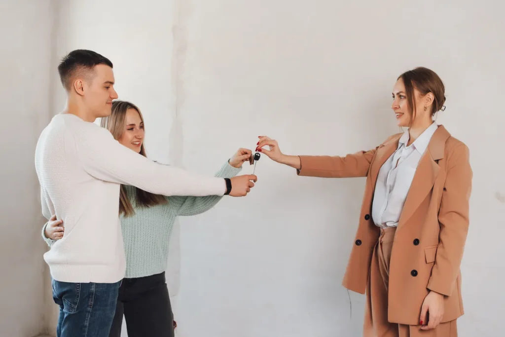 Couple recevant les clés de son logement des mains de l'agent immobilier