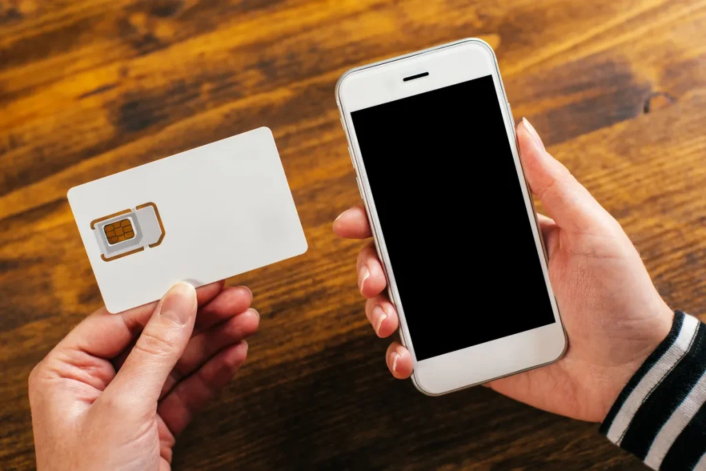 Mains tenant une carte SIM et un smartphone avant la résiliation d'un forfait mobile