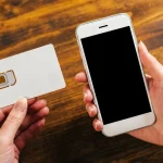 Mains tenant une carte SIM et un smartphone avant la résiliation d'un forfait mobile