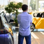 Homme regardant des voitures neuves dans une concession automobile