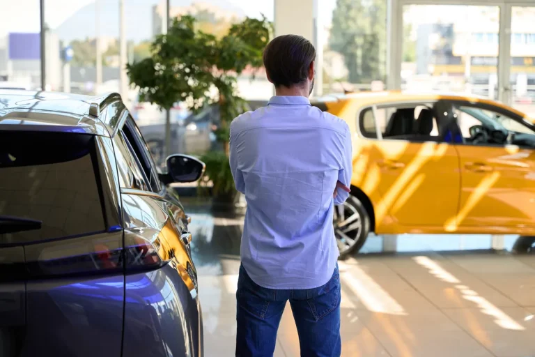 Homme regardant des voitures neuves dans une concession automobile