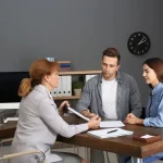 Jeune couple reçu par un conseiller bancaire avant de signer un crédit