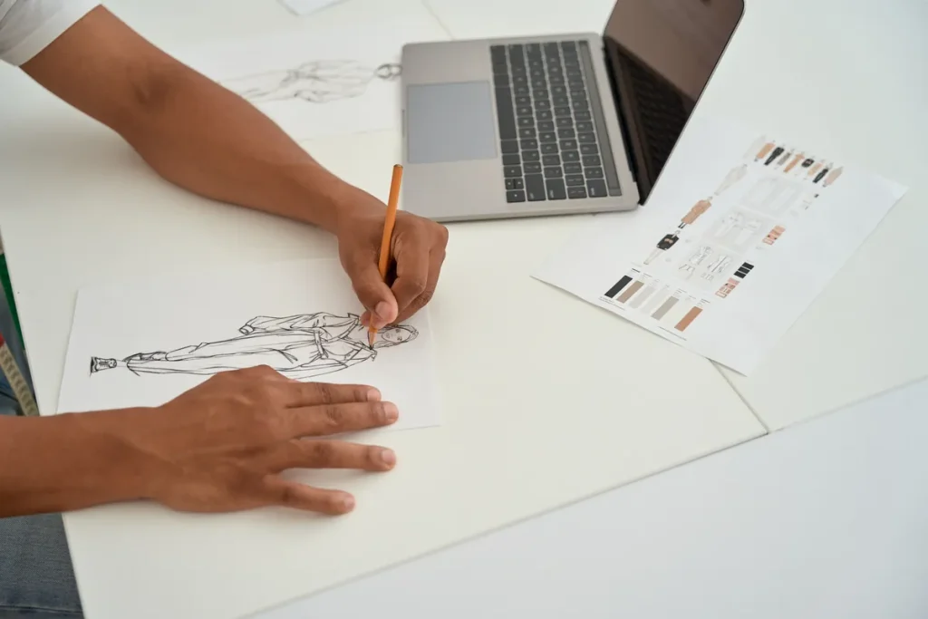 Styliste dessinant une robe à son bureau, création à protéger par une marque
