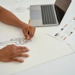 Styliste dessinant une robe à son bureau, création à protéger par une marque