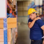 Ouvrier d'entrepôt se tenant l'épaule douloureuse, possible maladie professionnelle