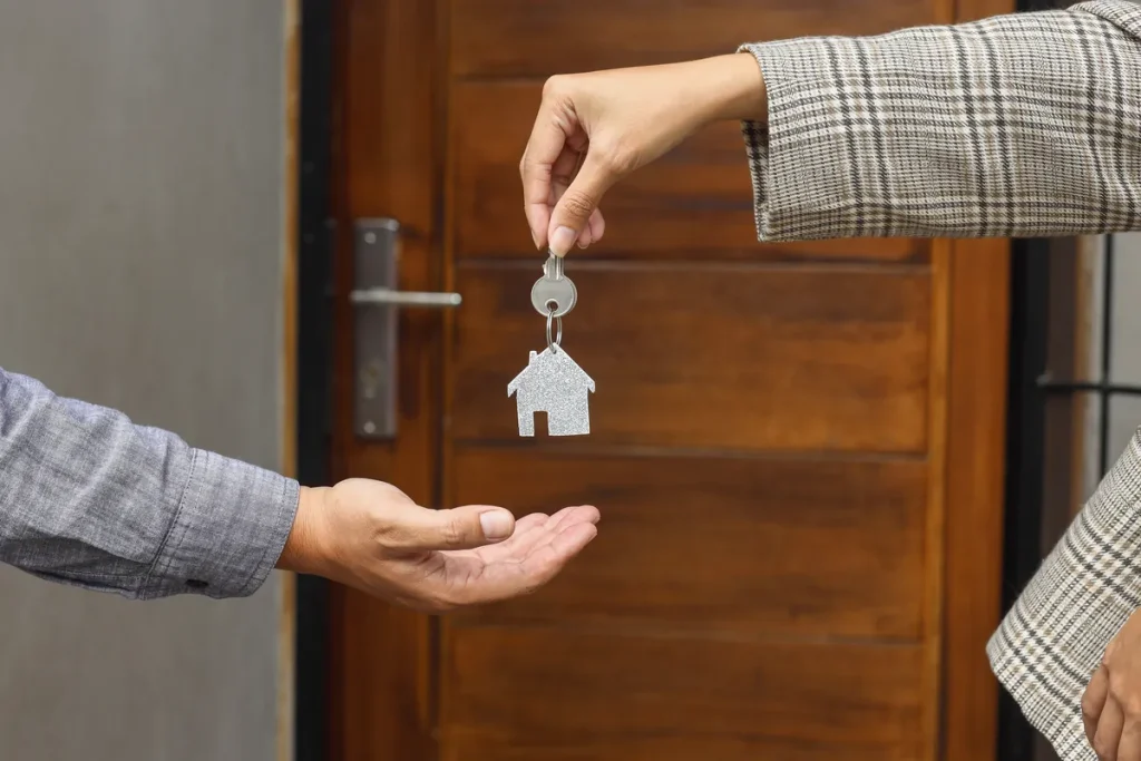 Remise des clés d'un logement devant la porte d'entrée, entre propriétaire et locataire